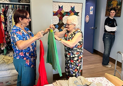 two elderly women looking at eachothers wardrobes